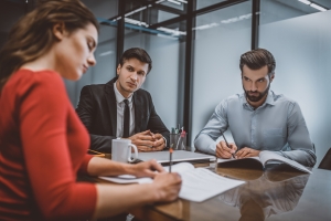 Couple Writing a High-Asset Divorce Request in Attorney Office
