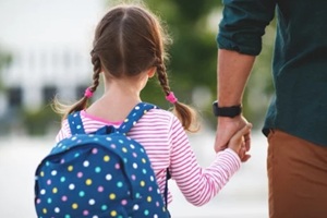 father leads little child school girl in first grade