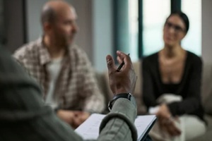 middle aged couple attending counseling session, listening during divorce mediation with therapist taking notes