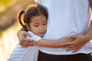 sad asian child girl hugging her mother in the paddy field with the sunlight