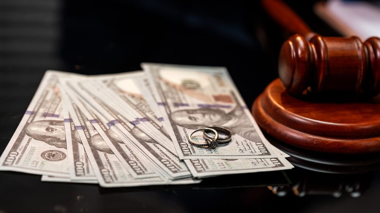wedding rings and us dollar bills beside a judge gavel
